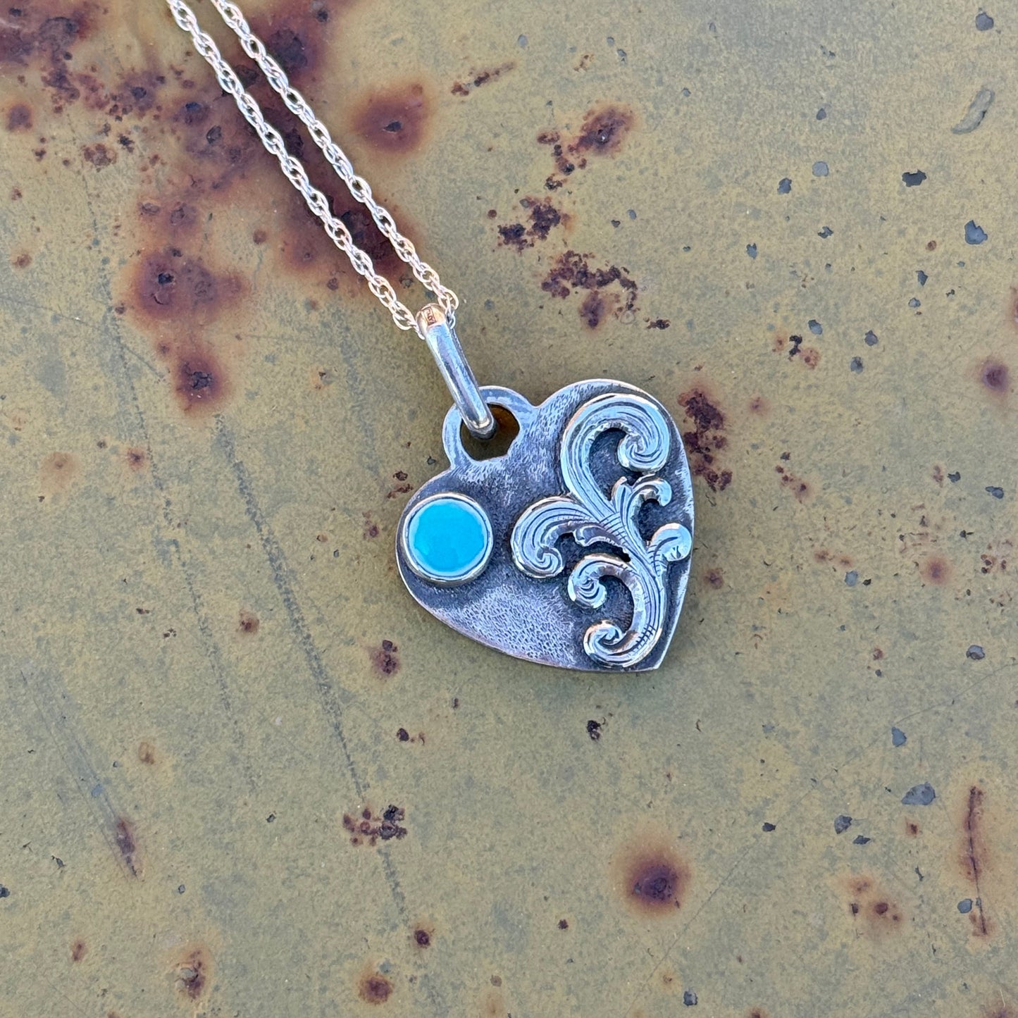 Silver pendant with a turquoise cabochon on a textured surface