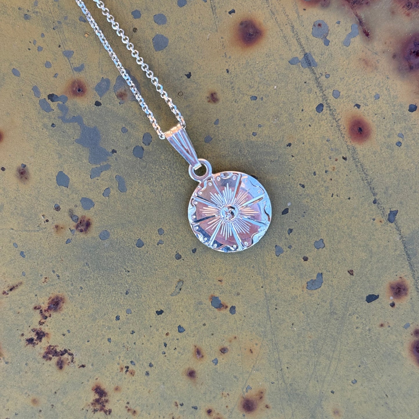 Silver necklace with a round pendant on a rustic background