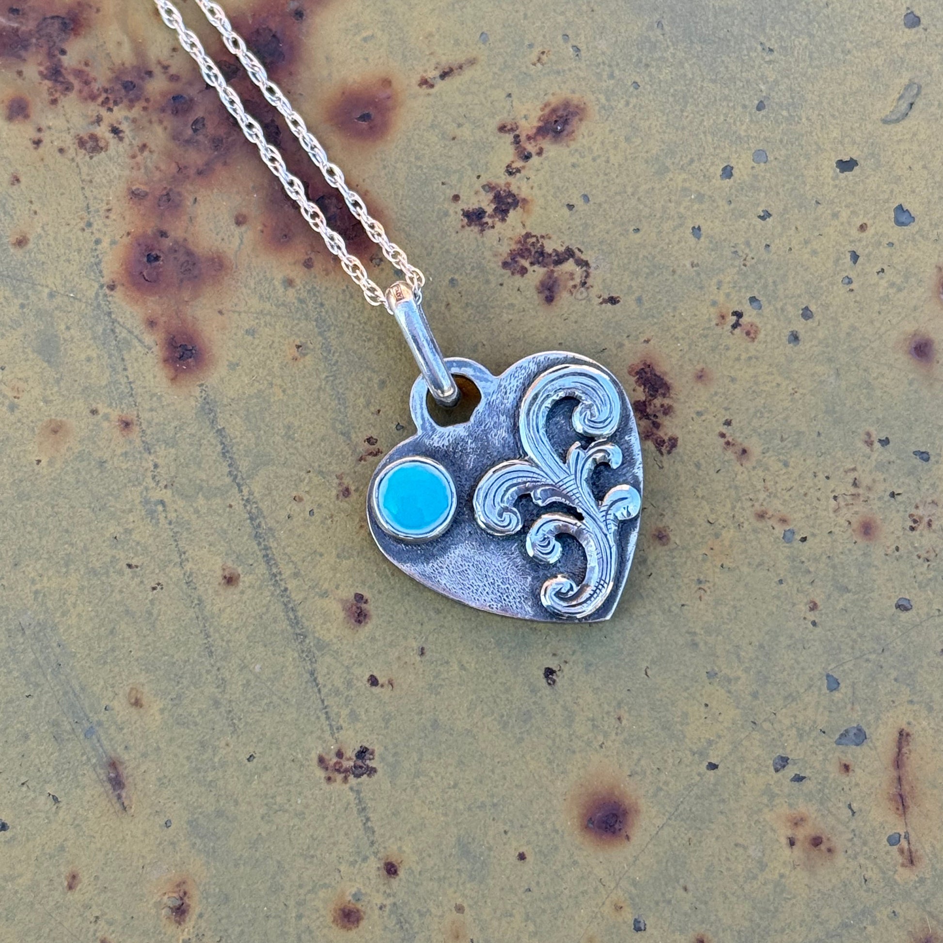 Silver pendant with a turquoise cabochon  on a textured surface