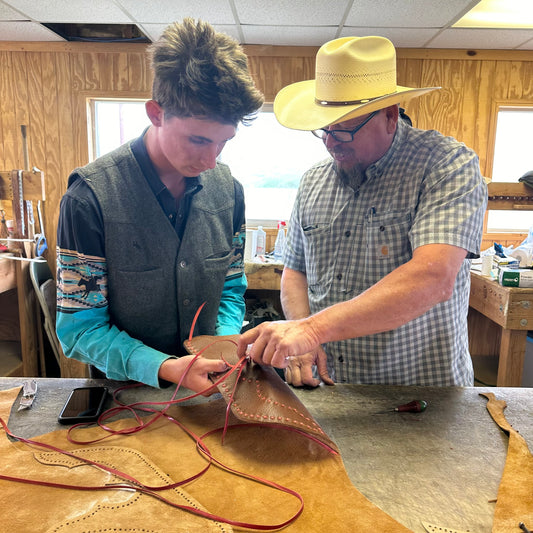 Two men working on leatherwork in a workshop setting.