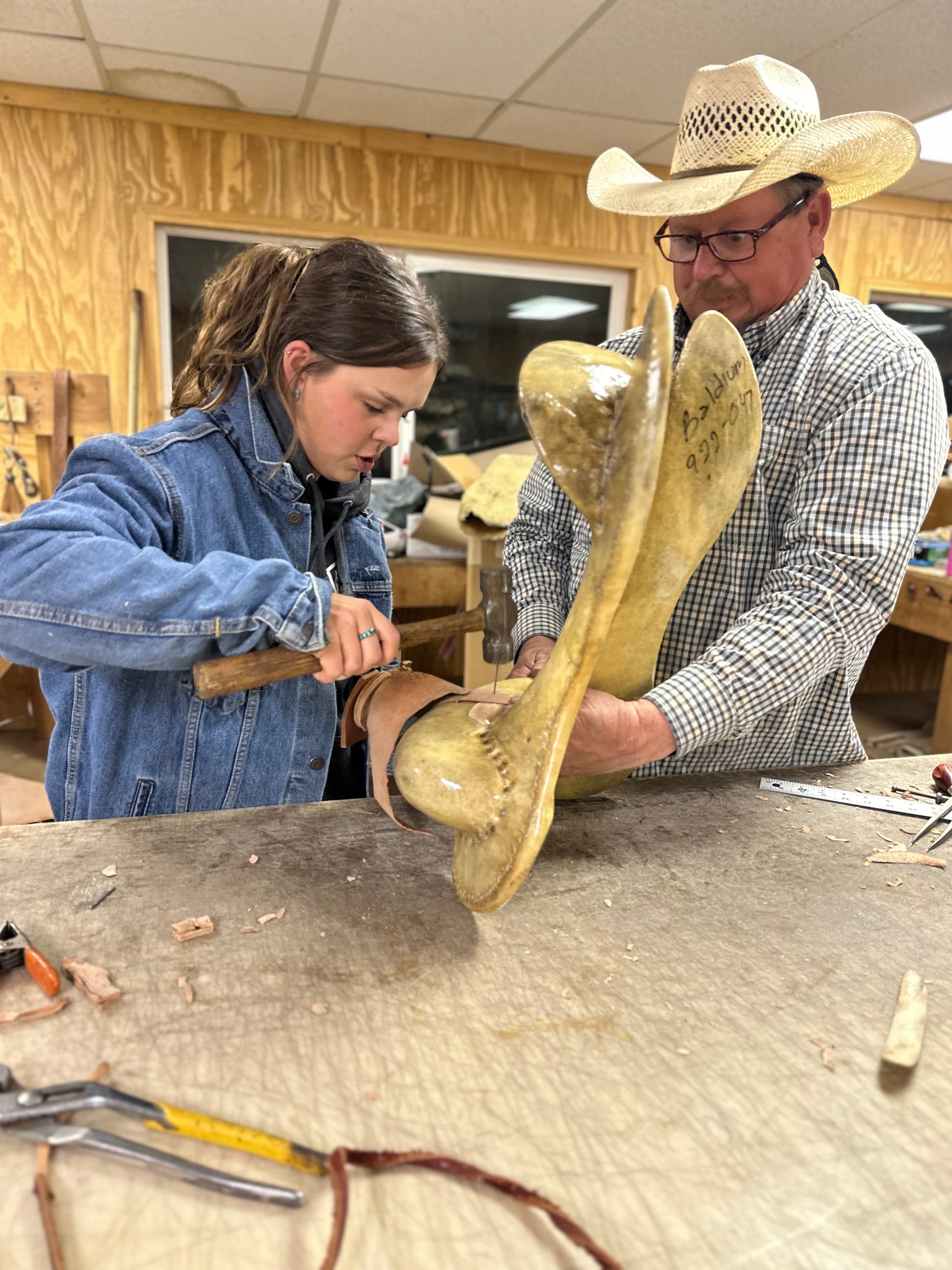 Two people working on a saddle tree in the shop