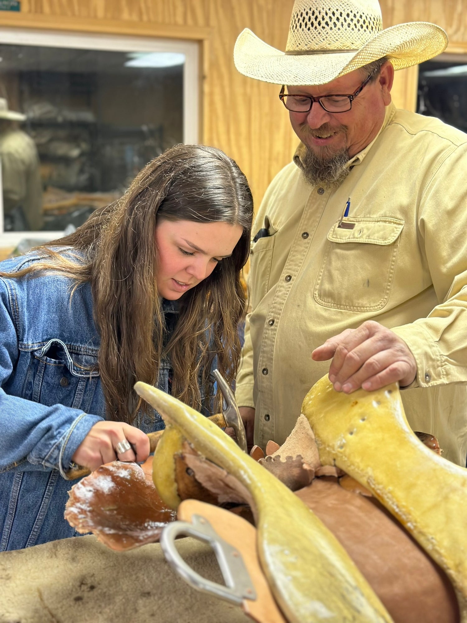 Instructor and student hammering a nail into a saddle tree