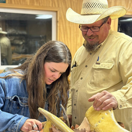 Instructor and student hammering a nail into a saddle tree