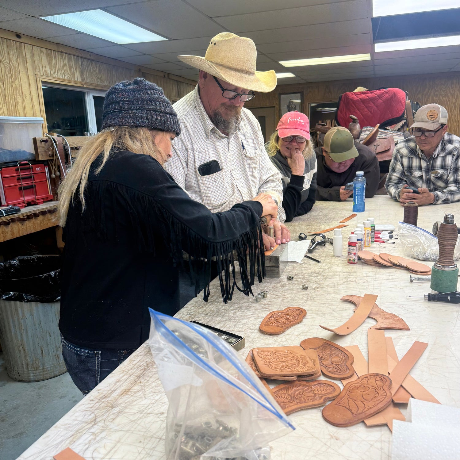 People gathered around a table with various items including cookies and a laptop.