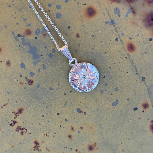 Silver necklace with a round pendant on a rustic background